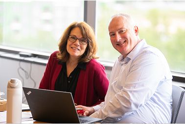 Two people with laptop smiling at camera